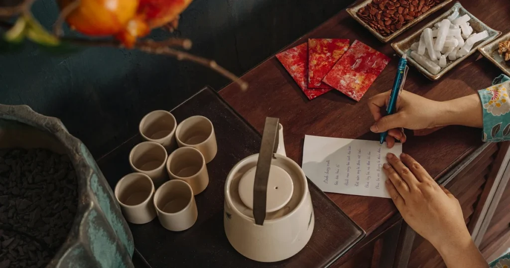 Hands arranging herbal tea and handwritten notes on a wooden table during morning light, symbolizing preparation and contemplation before a wellness decision.