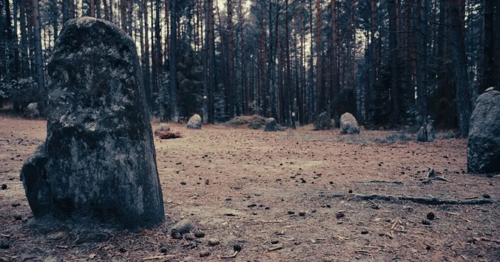 Weathered ancient stone monument in a Nordic forest clearing under gray overcast daylight